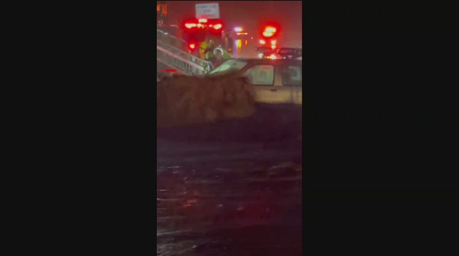 A driver is pulled rescued from a car during major flooding in California