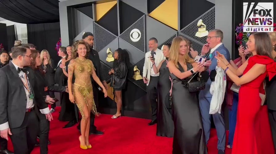 Miley Cyrus walks red carpet at Grammys in gold