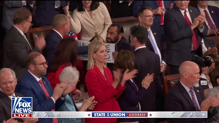 Rep. Steve Scalise, R-La., grabs at race sign of Rep. Al Green, D-Texas, on Tuesday night at the State of the Union.