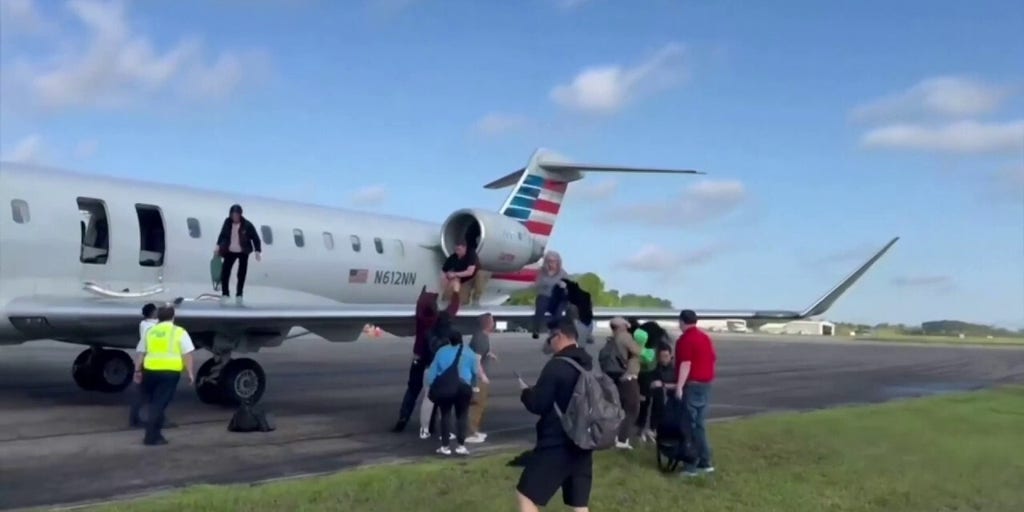 American Airlines passengers evacuate on plane's wing after landing