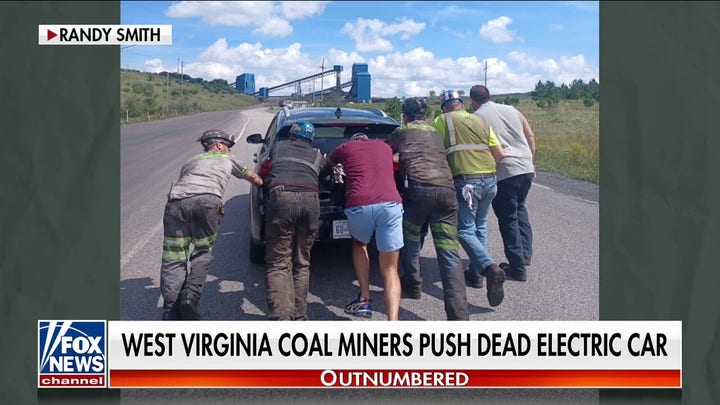 Coal miners shown pushing broken down electric vehicle