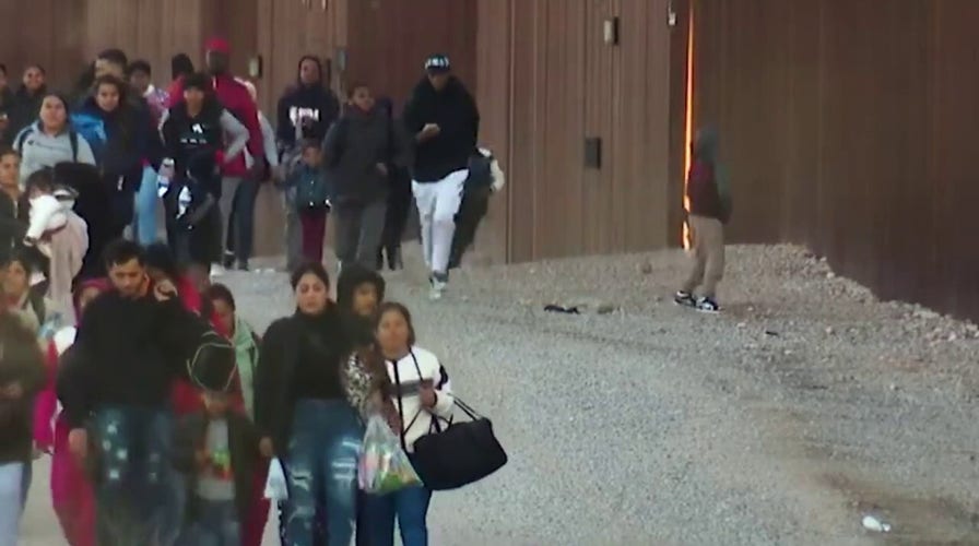 WATCH: Dozens of migrants breach border wall, take selfies on US side