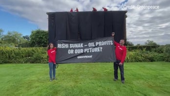 Greenpeace climate protesters climb atop UK prime minister's home, hang black fabric