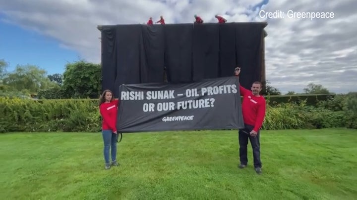 Greenpeace climate protesters climb atop UK prime minister's home, hang black fabric