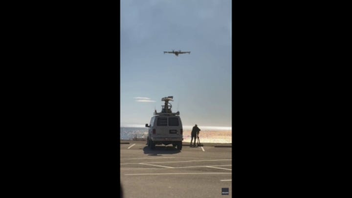 A firefighter plane scoops ocean water to battle Southern California wildfires