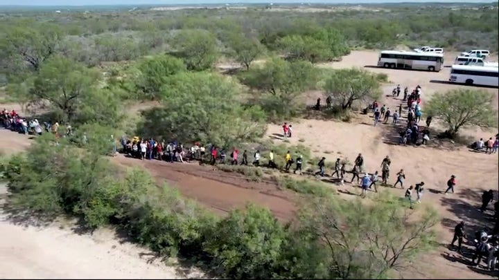 Drone footage shows a large group of migrants crossing the US-Mexico border