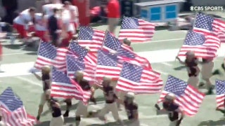 Players run out  with American flags in support of victims of the 9/11 attacks