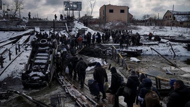 Photos show Ukrainians traversing broken bridges to flee as those at home bury their dead