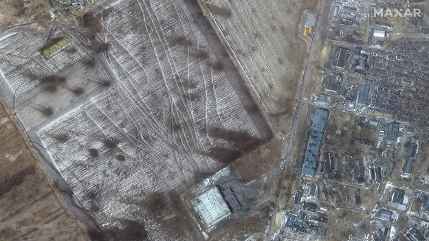 Satellite imagery of artillery craters in fields and damaged buildings in western Mariupol