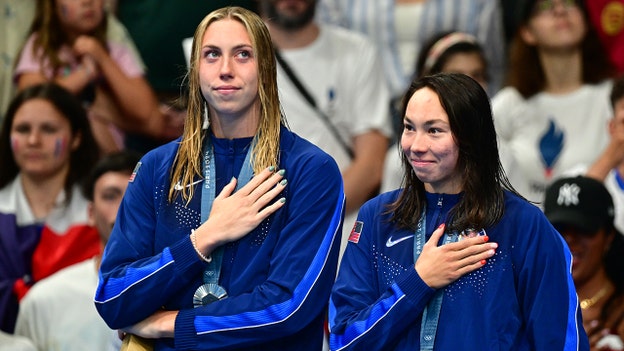 Torri Huske, del Equipo de EE.UU., comparte el escenario de la medalla de oro con su compañera de equipo antes del himno nacional