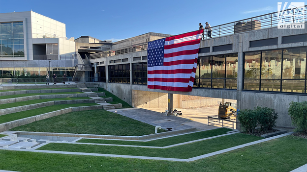 Una gran bandera estadounidense cuelga sobre el lugar donde Charlie Kirk realizó la sesión fotográfica en la Universidad Utah