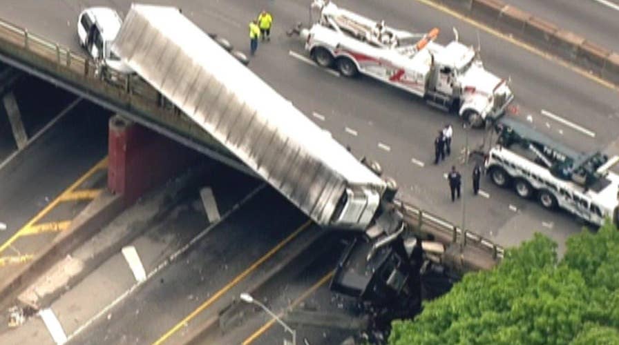 Frightening crash leaves truck dangling from overpass