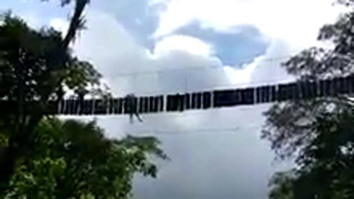 Person hangs from rope bridge after deadly collapse