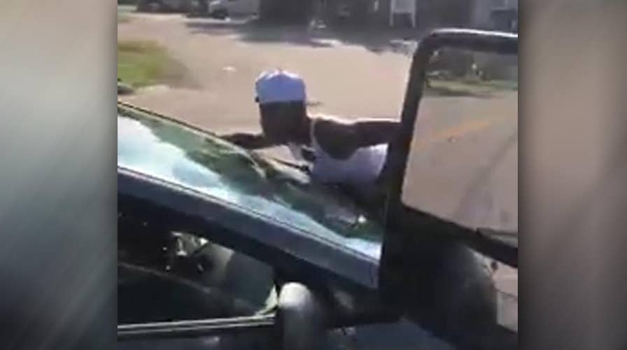 'She's trying to kill me!' Woman clings to car on busy road