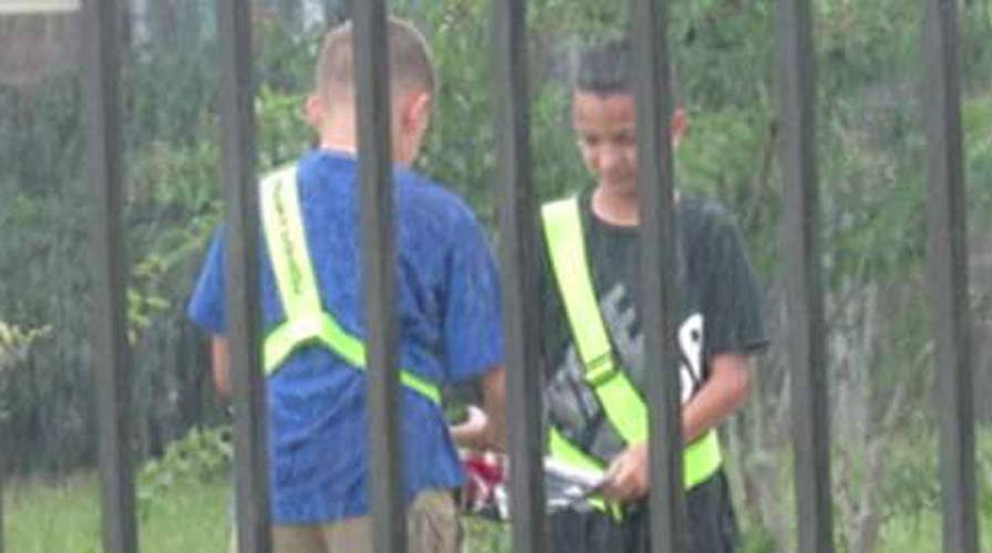 Two elementary school students fold flag in the pouring rain