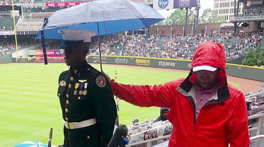 Baseball fan holds an umbrella over a JROTC cadet