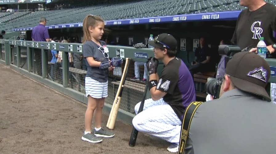 Girl with robotic hand throws out first pitch at baseball game