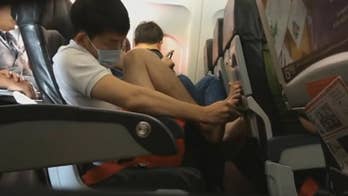 AirAsia passenger caught on video picking dry skin off bare foot and dropping it onto plane floor