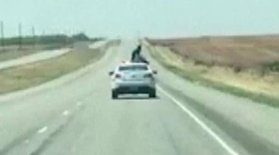 Prisoner climbs on top of police car in escape attempt