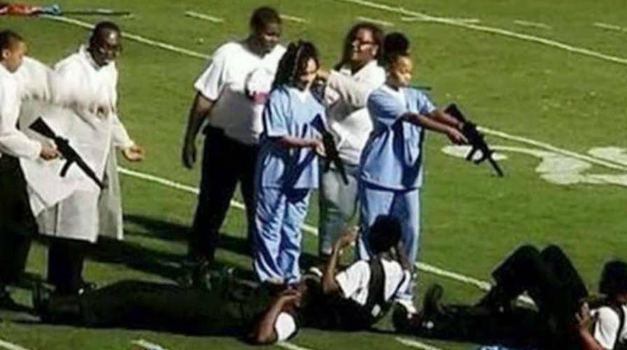 School marching band depicts kids pointing guns at cops