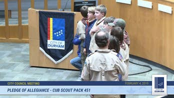 North Carolina Cub Scout, 10, kneels during Pledge of Allegiance at city council meeting