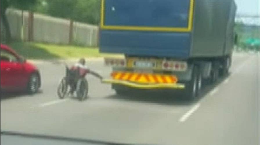 Man in wheelchair hangs onto truck speeding down South African highway