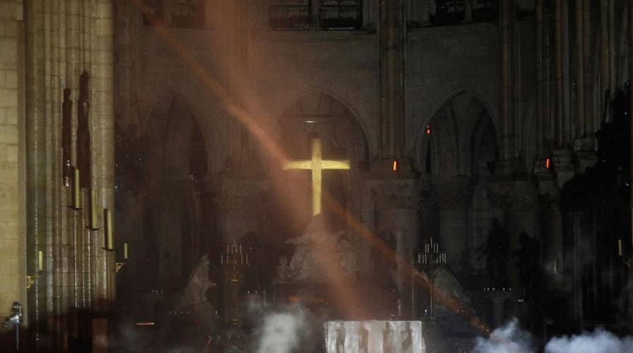 Notre Dame’s golden altar cross seen glowing among the ashes as images emerge from inside show fire-ravaged cathedral