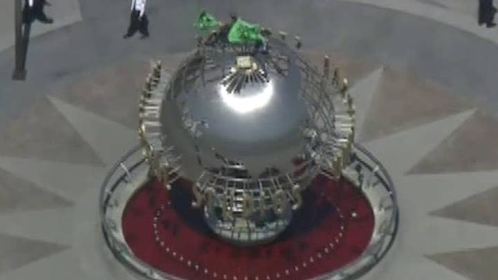 Climate change protestors climb on top of the globe at Universal Studios in California