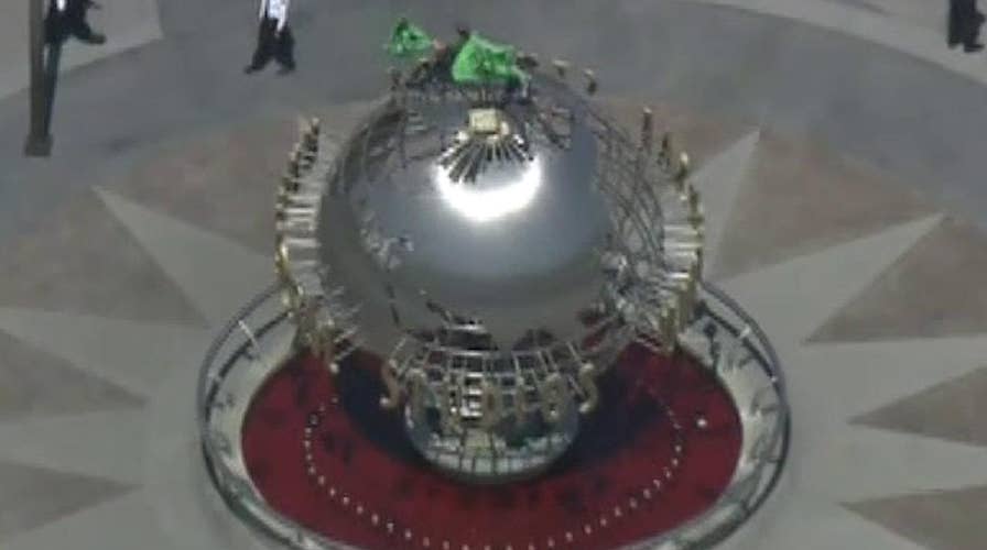 Climate change protestors climb on top of the globe at Universal Studios in California