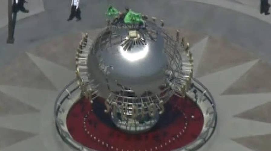 Climate change protestors climb on top of the globe at Universal Studios in California
