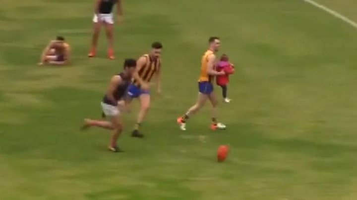 Toddler who ran onto field during game gets carried away by Australian rules football player