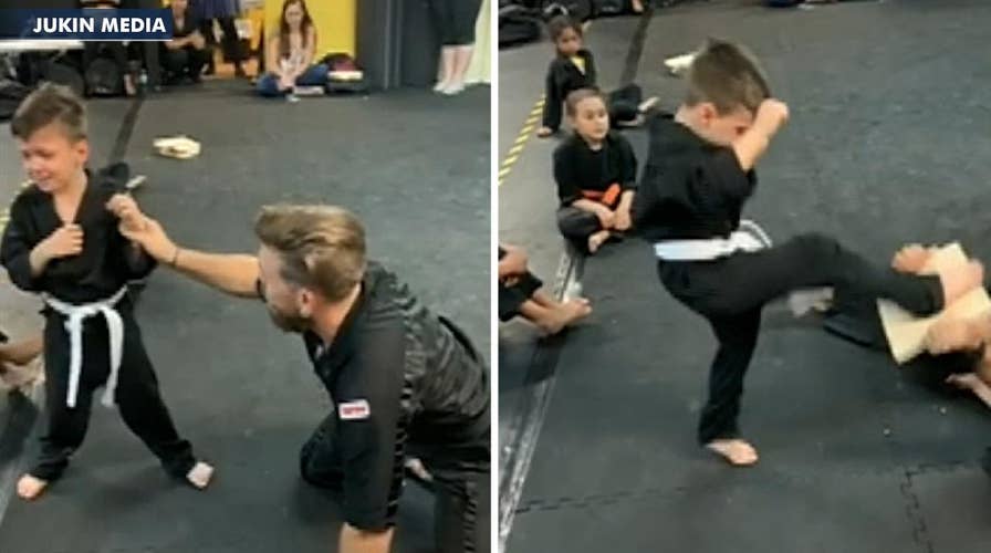 Karate class cheers on student having trouble breaking board