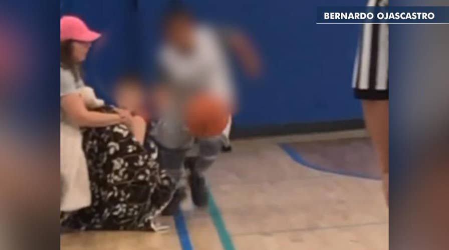 Parent sitting courtside appears to stick leg out as youth basketball player dribbles past