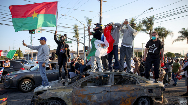 Mob standing on burned out car - Fox News