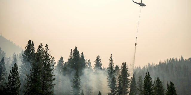 A helicopter drops water on a hot spot while battling the McKinney Fire on Tuesday, Aug. 2, 2022, in Klamath National Forest, Calif.