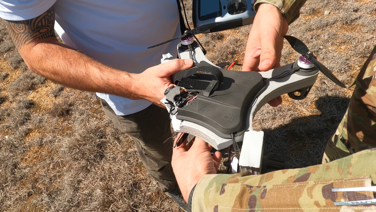 Military men hold a damaged 3D printed drone that can be restored and used again for training purposes. 