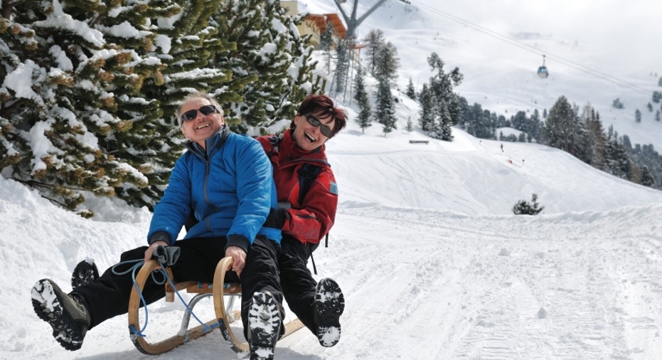 Senior couple on sledge having fun