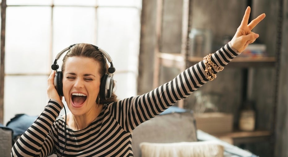 Cheerful Young Woman Listening Music In Headphones In Loft Apart