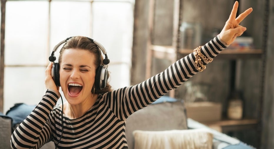 Cheerful Young Woman Listening Music In Headphones In Loft Apart