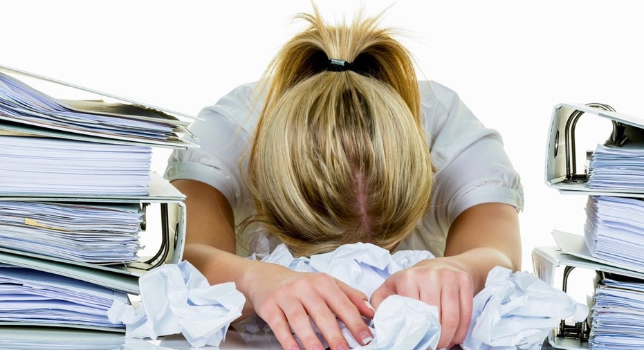 a young woman desperately in office between many file folders and crumpled papier.symbolfoto for str