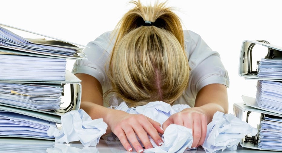 a young woman desperately in office between many file folders and crumpled papier.symbolfoto for str