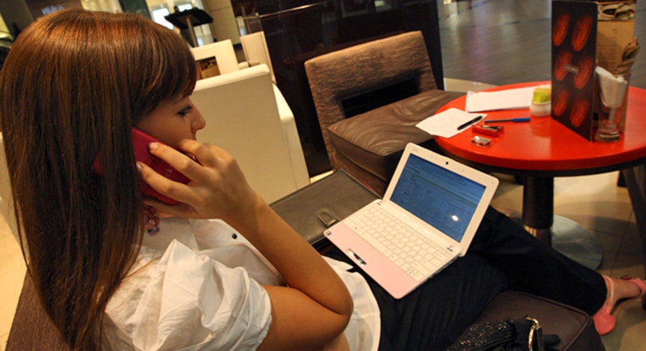 Woman on Phone Using Netbook in Cafe reuters