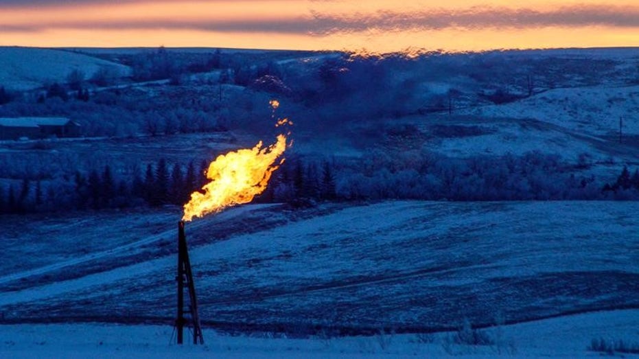 A natural gas flare on an oil well pad burns as the sun sets outside Watford City, North Dakota, Jan. 21, 2016. 