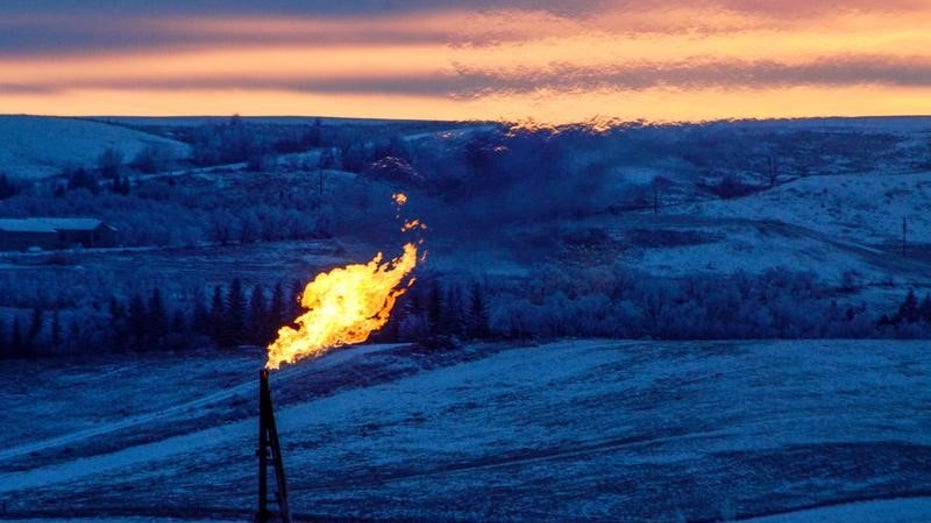A natural gas flare on an oil well pad burns as the sun sets outside Watford City, North Dakota, Jan. 21, 2016.