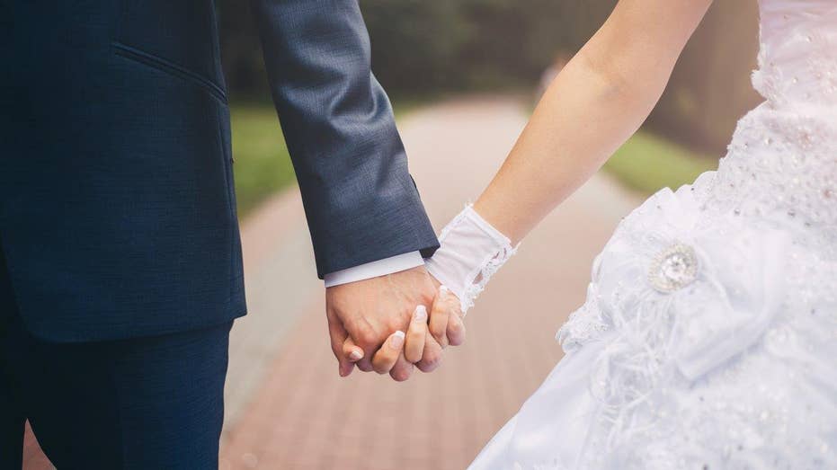 Newlyweds hold hands while they walk.