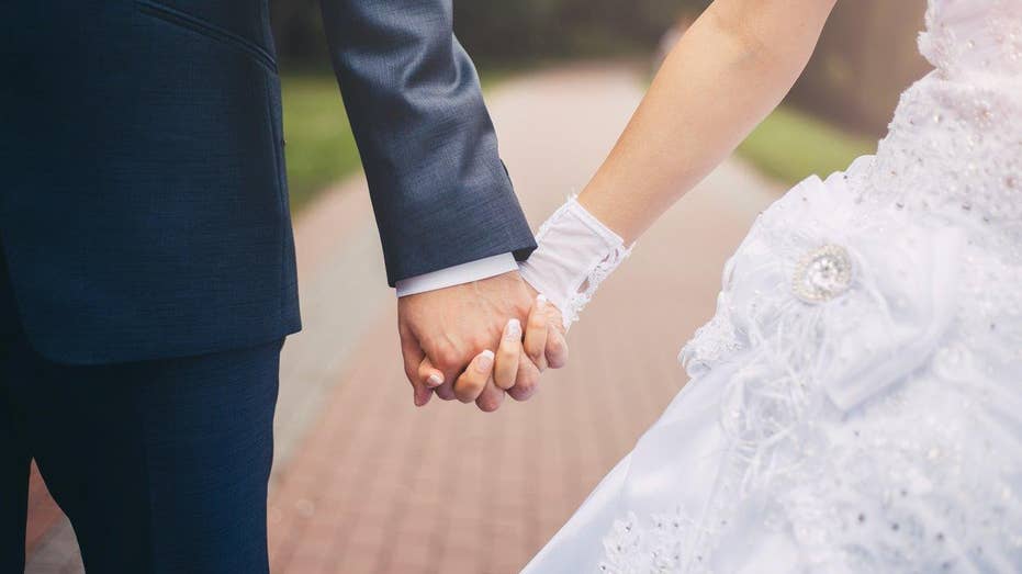 Newlyweds hold hands while they walk.