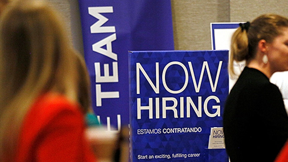 A now hiring sign is seen at a job fair