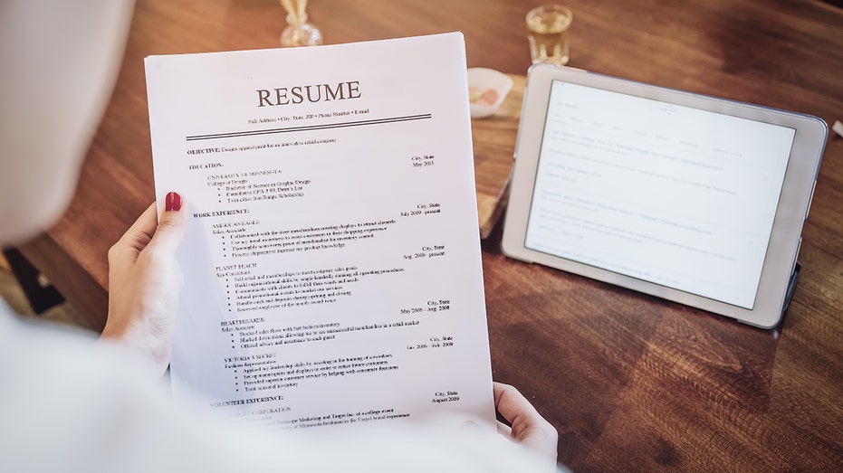 Woman holds resume over tablet
