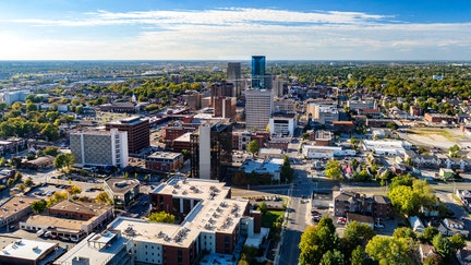 Aerial view of Downtown Lexington, Kentucky with a blue sky with clouds and the metropolitan area cityscape in the background.