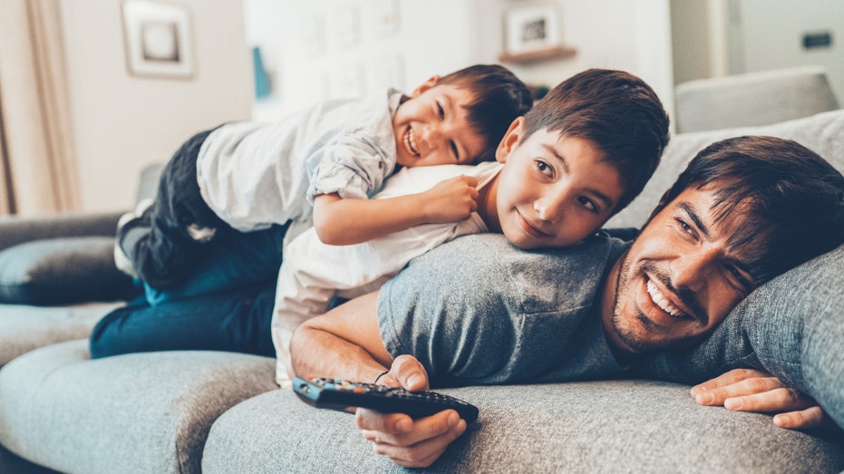 Father watches tv with sons